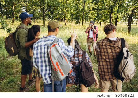 Group of friends, young men and women walking, strolling together during picnic in summer forest, meadow. Lifestyle, friendship, 80868823