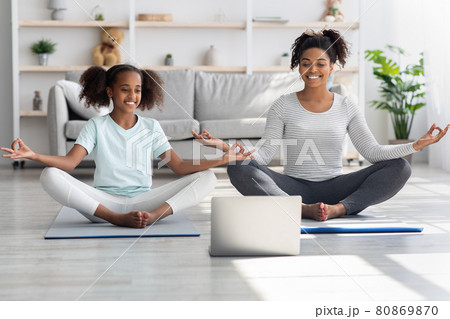 Cheerful black mom and daughter having online yoga class 80869870