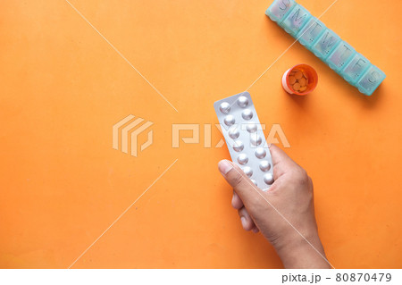 man holding blister packs with medicine container and pill box on table man holding blister packs with medicine container and pill box on table 80870479