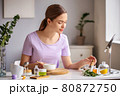 A woman in a room, preparing natural purple blush cosmetic. 80872750