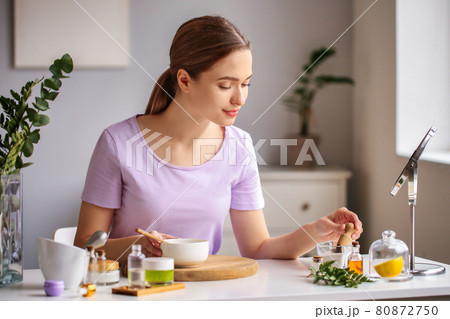 A woman in a room, preparing natural purple blush cosmetic. A woman in a room, preparing natural purple blush cosmetic. 80872750