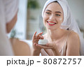 Beautiful woman smiling in the mirror with a jar of cream in her hands. 80872757