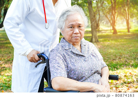 Doctor help and care Asian senior or elderly old lady woman patient sitting on wheelchair at park in nursing hospital ward : healthy strong medical concept . 80874163