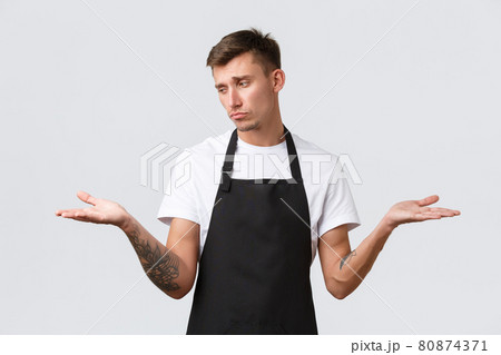 Cafe and restaurants, coffee shop owners and retail concept. Disappointed gloomy waiter, salesman in black apron sighing upset, showing two variants on palms and looking sad at left hand Cafe and restaurants, coffee shop owners and retail concept. Disappointed gloomy waiter, salesman in black apron sighing upset, showing two variants on palms and looking sad at left hand 80874371