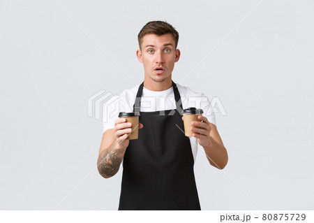 Small business, coffee shop, cafe and restaurants concept. Handsome barista, waiter giving out takeaway coffee in paper cups, prepared order for guests, selling drinks over white background 80875729