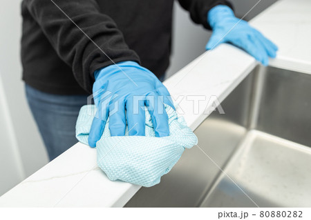 Hands in protective glove cleaning a modern sink with rag of a minimalist domestic kitchen Hands in protective glove cleaning a modern sink with rag of a minimalist domestic kitchen 80880282