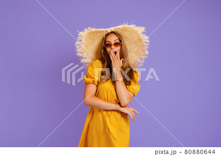 elegant woman in a light dress with a straw hat on her head holds the other on her neck 80880644