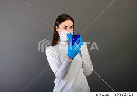 Girl in medical gloves dress a medical mask on her face on a background. Respiratory disease. Covid-19 Girl in medical gloves dress a medical mask on her face on a background. Respiratory disease. Covid-19 80882712