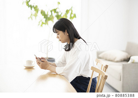 リビングでスマホを操作する若い女性 80885388