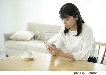 リビングでスマホを操作する若い女性 80885393