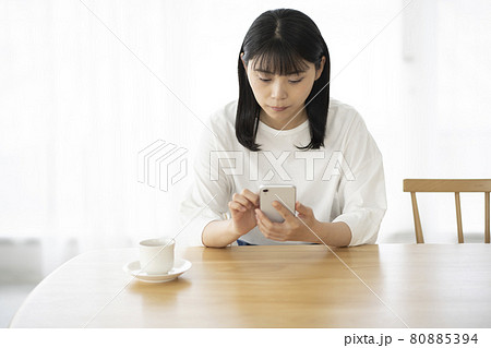 リビングでスマホを操作する若い女性 80885394