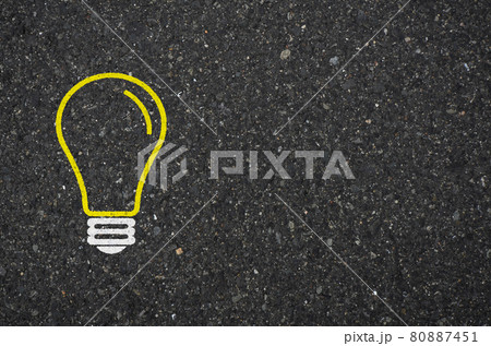 アスファルト道路に閃きイメージの電球標識の背景素材 80887451
