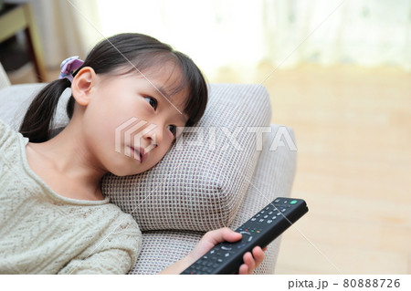 ソファに寝転んでテレビを見る幼児の女の子 80888726