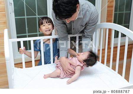 新生児を抱っこしてベッドに寝かしつけをするパパ 80888787