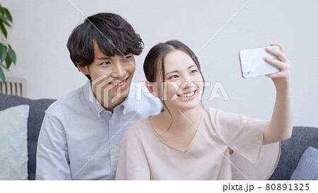 スマホで自撮りをする若い夫婦 カップルの写真素材
