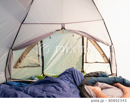 Green tent inside with naked children legs and blue sleeping bags. 80892343