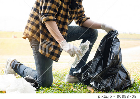 Man's hands pick up plastic bottles, put garbage in black garbage bags to clean up at parks, avoid pollution, be friendly to the environment and ecosystem 80893708