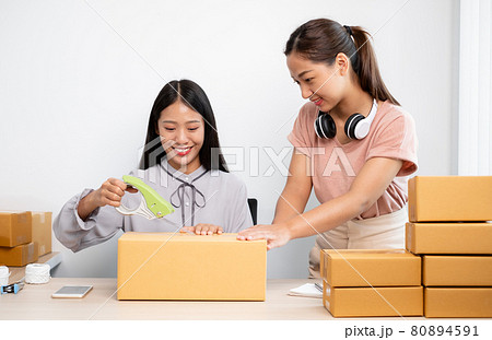 An Asian businesswoman, two owners with lots of boxes on their desks, happy to sell online, take orders from customers, and arrange their mail delivery 80894591