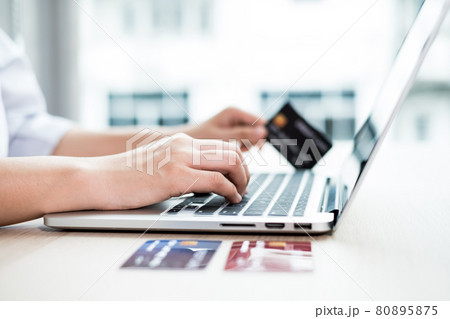 The businesswoman's hand is holding a credit card and using a laptop for online shopping and internet payment in the office 80895875
