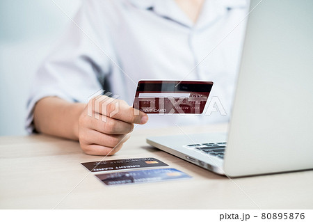 The businesswoman's hand is holding a credit card and using a laptop for online shopping and internet payment in the office 80895876