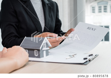 A real estate agent with a home model is talking to clients about renting a home and buying home insurance. Home rental and insurance concept 80895878