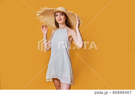 Pretty glamorous girl touching her straw hat. Studio portrait of joyful young woman Pretty glamorous girl touching her straw hat. Studio portrait of joyful young woman 80896407