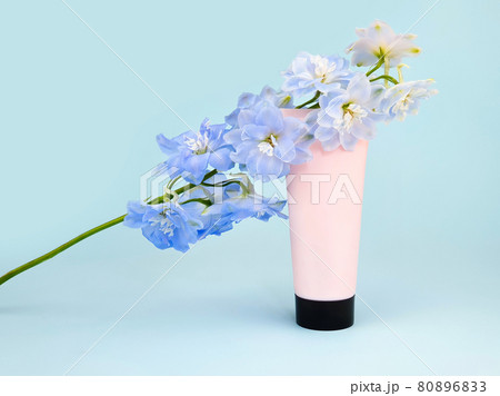 Unbranded pink squeeze bottle cream tube with black screw cap and blue Delphinium flower on blue background. Skincare beauty, mockup. Cosmetic bottle blank for branding and label, front view, closeup. Unbranded pink squeeze bottle cream tube with black screw cap and blue Delphinium flower on blue background. Skincare beauty, mockup. Cosmetic bottle blank for branding and label, front view, closeup. 80896833