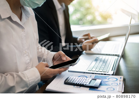 Business people discussing on performance revenue in meeting.mask for corona virus. financial adviser analyzing data with investor at office. Business people discussing on performance revenue in meeting.mask for corona virus. financial adviser analyzing data with investor at office. 80898170