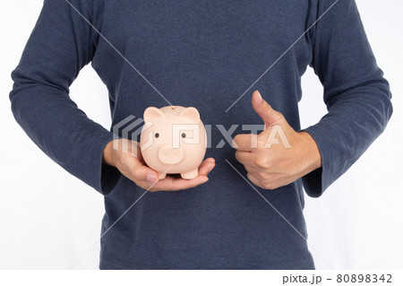 Man holding a pink piggy bank and showing thumbs up isolated on white background Man holding a pink piggy bank and showing thumbs up isolated on white background 80898342