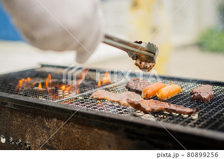 バーベキューで肉を焼く手 80899256