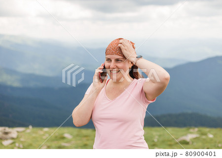 Young female traveler talking on the phone in the mountains. Connectivity mobility technology. Travel Lifestyle sport and extreme, adventure activities. 80900401