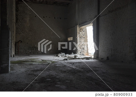 Abandoned empty warehouse with cracked concrete walls, broken bricks and light falling through open door. Abandoned empty warehouse with cracked concrete walls, broken bricks and light falling through open door. 80900933