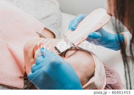 Moisturizing the face and removing keratinized old skin, the beautician uses ultrasound with microvibrations. Moisturizing the face and removing keratinized old skin, the beautician uses ultrasound with microvibrations. 80901455