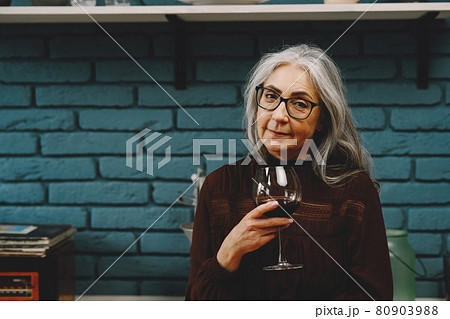 Portrait of beautiful happy senior woman with glass of red wine at home 80903988