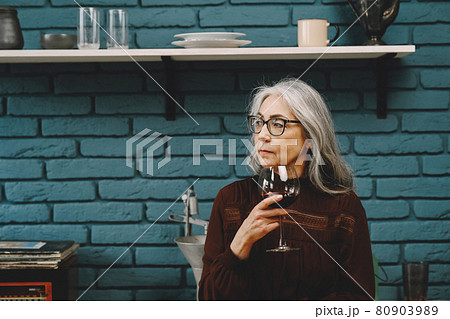 Portrait of beautiful happy senior woman with glass of red wine at home 80903989