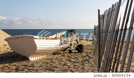 White lifeguards row boat on the sand next to a fence at Sunken Meadow State Park 80904234