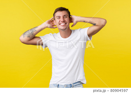 Lifestyle, summer and people emotions concept. Carefree handsome happy man with white cheerful smile, holding hands behind head, enjoying vacation, standing yellow background Lifestyle, summer and people emotions concept. Carefree handsome happy man with white cheerful smile, holding hands behind head, enjoying vacation, standing yellow background 80904597