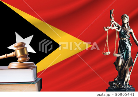 Law and justice in East Timor. Statue of themis and the gavel of the judge against the background of the flag of East Timor. Law and justice concept 80905441
