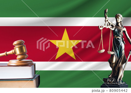Law and justice in Suriname. Statue of themis and the gavel of the judge against the background of the flag of Suriname. Law and justice concept Law and justice in Suriname. Statue of themis and the gavel of the judge against the background of the flag of Suriname. Law and justice concept 80905442