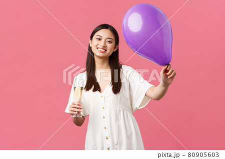 Celebration, party holidays and fun concept. Tender pretty asian woman in white dress, holding balloon and glass champagne, making toast during event, congratulating hosts, pink background Celebration, party holidays and fun concept. Tender pretty asian woman in white dress, holding balloon and glass champagne, making toast during event, congratulating hosts, pink background 80905603