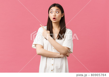 Beauty, people emotions and summer leisure concept. Surprised and curious cute female customer in shopping center, wearing dress, gasping and open mouth shocked as pointing upper left corner Beauty, people emotions and summer leisure concept. Surprised and curious cute female customer in shopping center, wearing dress, gasping and open mouth shocked as pointing upper left corner 80905764