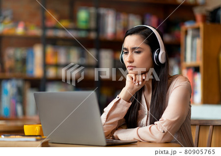 Online education concept. Concentrated latin woman studying online at cafe, using laptop and headset, copy space Online education concept. Concentrated latin woman studying online at cafe, using laptop and headset, copy space 80905765