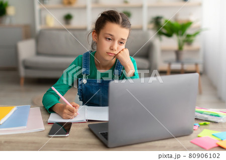 Tired school girl writing in notebook doing homework 80906102