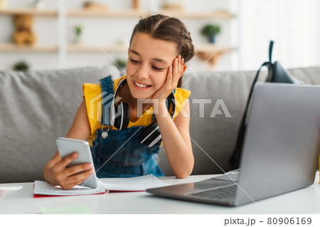 Girl sitting at desk, chatting on cell phone 80906169