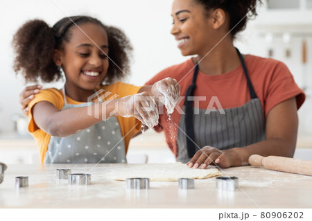 Closeup of happy black girl making cookies with her mom Closeup of happy black girl making cookies with her mom 80906202