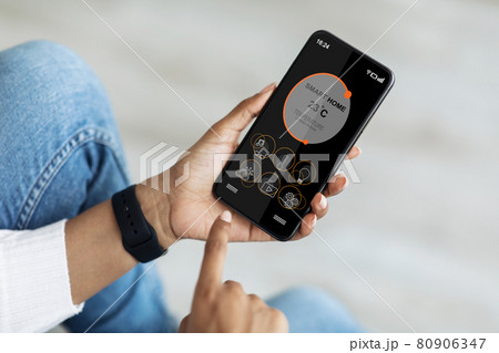 Black woman hands regulating air conditioner via mobile app Black woman hands regulating air conditioner via mobile app 80906347