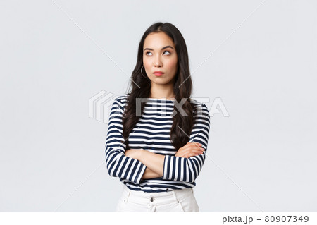 Lifestyle, beauty and fashion, people emotions concept. Annoyed and uninterested asian woman roll eyes, looking away bothered and bored, cross arms chest, standing white background 80907349