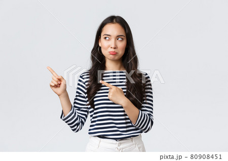 Lifestyle, beauty and fashion, people emotions concept. Disappointed sad asian girl complaining, feeling regret or jealousy as pouting uneasy and pointing fingers left at promo banner 80908451