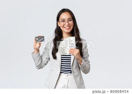 Business, finance and employment, entrepreneur and money concept. Successful asian businesswoman showing how increase income, hold credit card and money, smiling camera Business, finance and employment, entrepreneur and money concept. Successful asian businesswoman showing how increase income, hold credit card and money, smiling camera 80908454