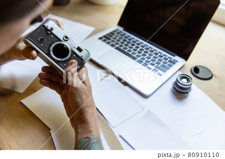 One young Caucasian man, photographer, cameraman with professional camera, equipment during working at office, indoors. Concept of occupation, job, education One young Caucasian man, photographer, cameraman with professional camera, equipment during working at office, indoors. Concept of occupation, job, education 80910110